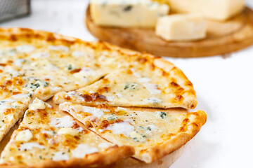 Pizza quattro formaggi on a wooden board .four cheese pizza and fresh ingredients for a four cheeses Italian pizza on a white wooden desk .