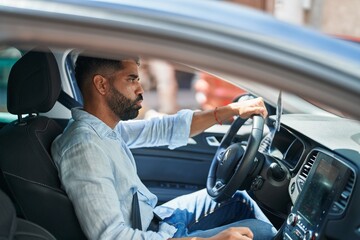 Young arab man stressed driving car at street