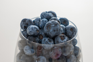 Glass bowl with blueberries on white table, close up.