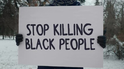 Person holding a placard with a solidarity slogan. Big white placard with a solidarity slogan Stop Killing Black People. Showing the solidarity toward people of colour with a slogan on a placard.