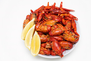 Red boiled crayfish with lemon on the plate isolated on a white background.