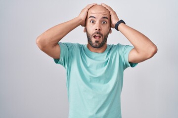 Middle age bald man standing over white background crazy and scared with hands on head, afraid and surprised of shock with open mouth