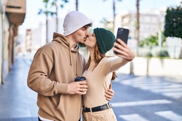 Mand and woman couple drinking coffee make selfie by smartphone at street