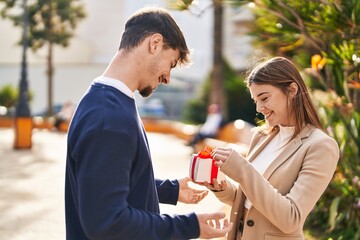 Mand and woman couple suprise with birthday gift standing together at park