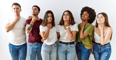 Group of young friends standing together over isolated background touching painful neck, sore...