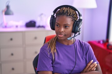African american woman streamer sitting with arms crossed gesture at gaming room