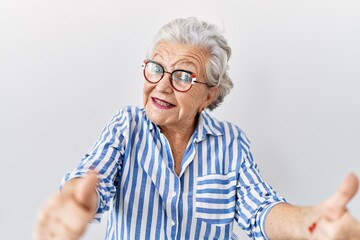 Senior woman with grey hair standing over white background approving doing positive gesture with hand, thumbs up smiling and happy for success. winner gesture.