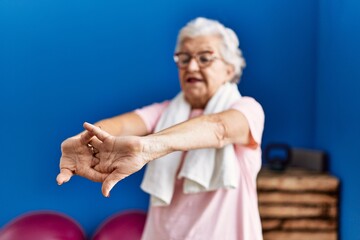 Senior grey-haired woman wearing sportswear smiling confident standing at sport center