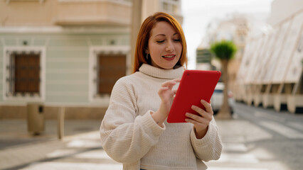 Young redhead woman smiling confident using touchpad at street