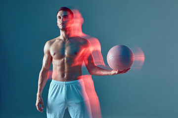 Sportive male with naked torso holding basketball ball on blue background. Long exposure. Sports...
