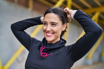 Young hispanic woman wearing sportswear combing hair with hands at street