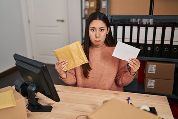 Young latin woman working at small business ecommerce packing order depressed and worry for distress, crying angry and afraid. sad expression.