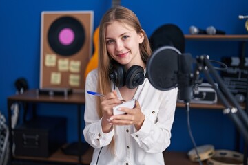 Young caucasian woman artist smiling confident composing song at music studio