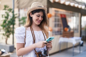 Young hispanic woman tourist smiling confident using smartphone at park