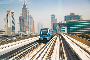 Dubai, UAE. Tube, metro railway track view with City buildings and approaching train