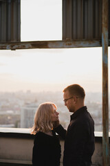 Romantic, young and happy caucasian couple in stylish clothes on the rooftop enjoying view and time together. Art portrait of beautiful woman and man. Love, relationships, romance, happiness concept.