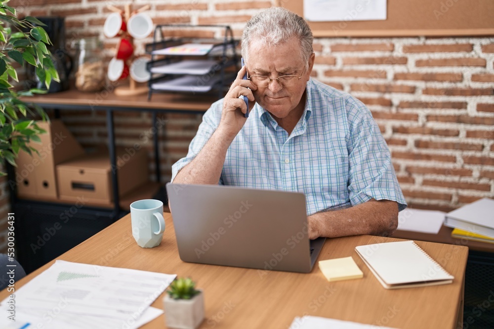 Sticker middle age grey-haired man business worker using laptop talking on smartphone at office