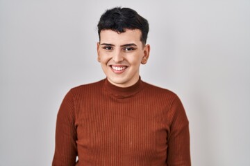 Non binary person wearing make up standing over isolated background looking positive and happy...