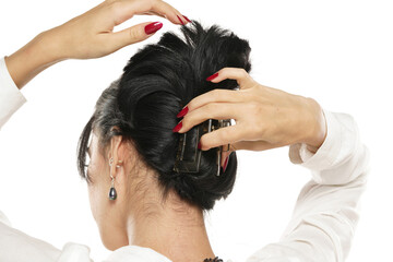 woman ties her hair with a barrette on a white background
