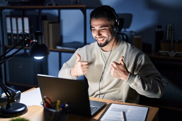 Fototapeta na wymiar Young handsome man working using computer laptop at night success sign doing positive gesture with hand, thumbs up smiling and happy. cheerful expression and winner gesture.