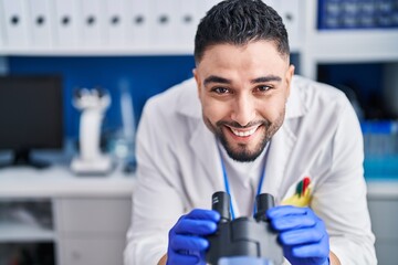 Young arab man scientist using microscope working at laboratory