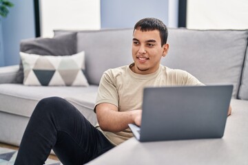 Young man using laptop sitting on floor at home