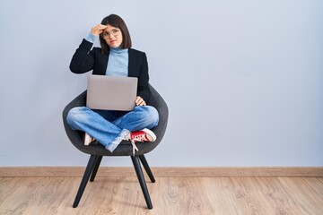 Young hispanic woman sitting on chair using computer laptop worried and stressed about a problem...
