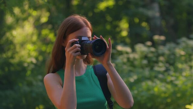 Young redhead girl photographer shooting nature scenery walks in reserve park in summertime. Creative hobby, travelling