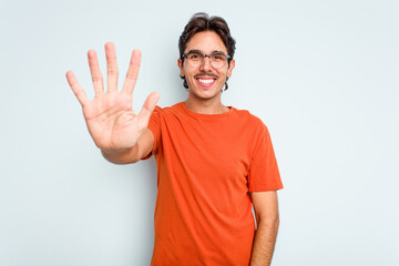 Fototapeta premium Young hispanic man isolated on blue background smiling cheerful showing number five with fingers.