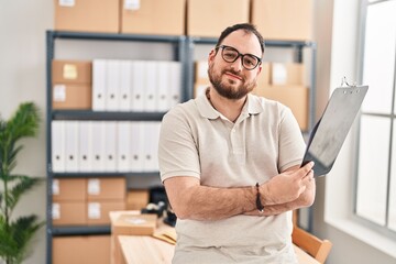 Young hispanic man e-commerce business worker holding clipboard at office