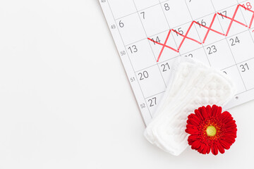 Fototapeta premium Calendar with red marks and white pad. Menstruation period concept