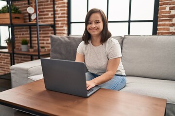 Naklejka premium Down syndrome woman using laptop sitting on sofa at home