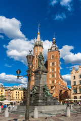 Fototapeta na wymiar Historic center of Krakow. Vintage lamppost, Adam Mickiewicz monument, St. Mary's Church and market square on a sunny day. Tourist attractions of Poland. Vertical Orientation