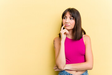 Young caucasian woman isolated on yellow background looking sideways with doubtful and skeptical expression.