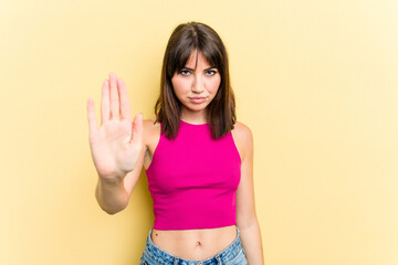 Young caucasian woman isolated on yellow background standing with outstretched hand showing stop...