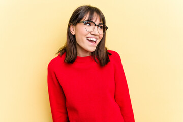 Young caucasian woman isolated on yellow background laughs and closes eyes, feels relaxed and happy.