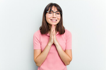 Young caucasian woman isolated on white background holding hands in pray near mouth, feels confident.