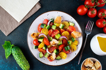 Vegetarian salad Panzanella with tomatoes, onion and bread Croutons. Dark background. Top view. Italian salad