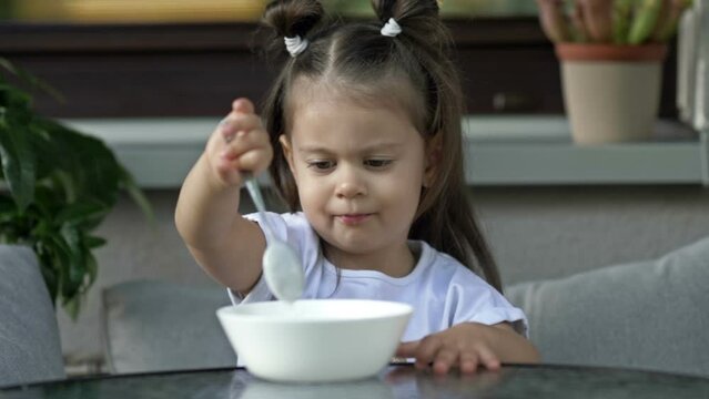 Cute little girl 2 years old does not want to eat porridge. Baby food concept.