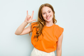 Fototapeta premium Young caucasian woman isolated on blue background showing a horns gesture as a revolution concept.