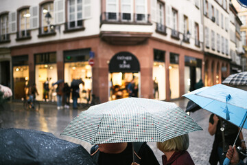 Rainy weather in the city - unexpected weather changes groupe of people Walking with umbrellas on pedestrian street