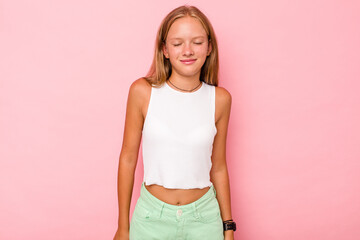 Caucasian teen girl isolated on pink background laughs and closes eyes, feels relaxed and happy.