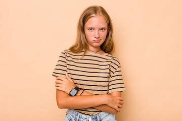 Caucasian teen girl isolated on beige background frowning face in displeasure, keeps arms folded.