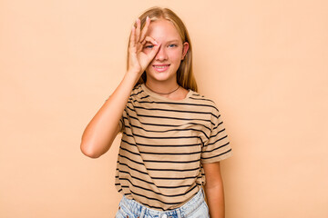 Caucasian teen girl isolated on beige background excited keeping ok gesture on eye.