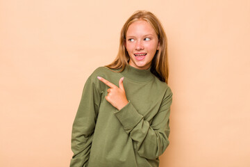 Caucasian teen girl isolated on beige background looks aside smiling, cheerful and pleasant.