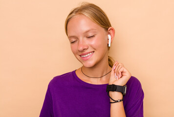 Little caucasian girl listening to music isolated on beige background