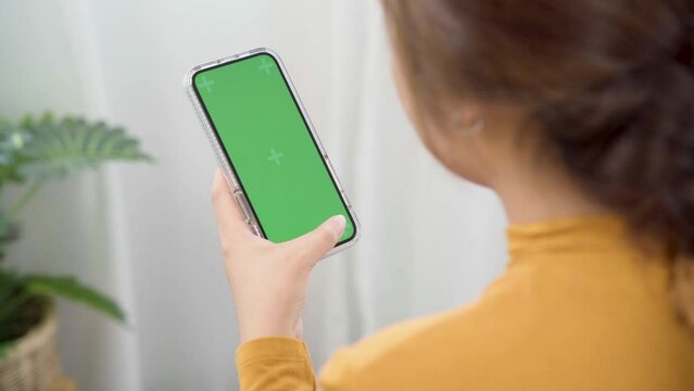 Woman Using Green Screen For Copy Space Closeup. Mock-up On Smartphone In Hand, Female Sitting On Bed Holding Mobile Phone And Touch Screen While Looking Social Network At Home.
