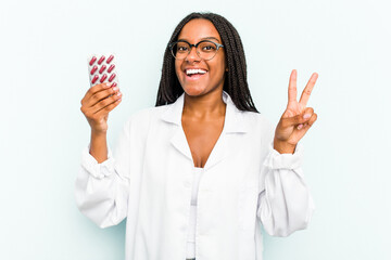 Young African American pharmacist woman isolated on blue background joyful and carefree showing a...