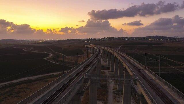 Beautiful aerial hyperlapse of two trains passing over a massive railway bridge in an orange sunset