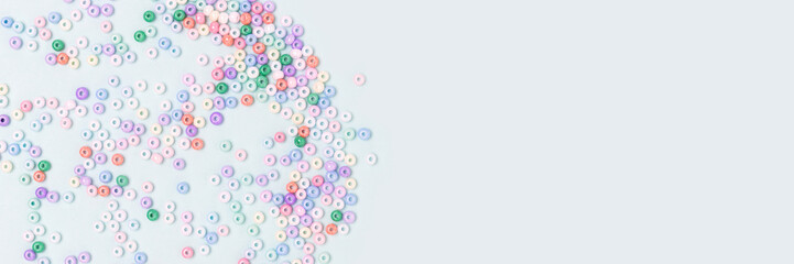 Banner with multicolored beads scattered on a blue pastel background. Equipment for handmade accessories.